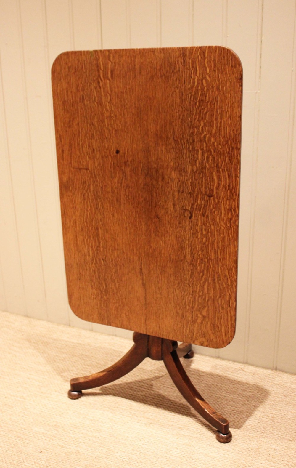 A late Georgian oak tilt-top table featuring a rectangular top with rounded corners, supported by a turned central column and a tripod base. View XII