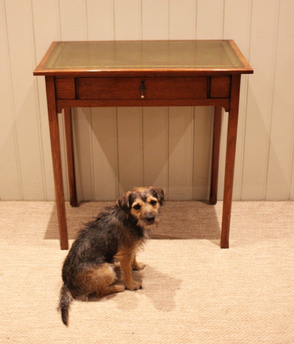 A small rectangular Arts and Crafts oak writing desk with a green gilded leather inset top, a single frieze drawer, and tapered square legs. View III