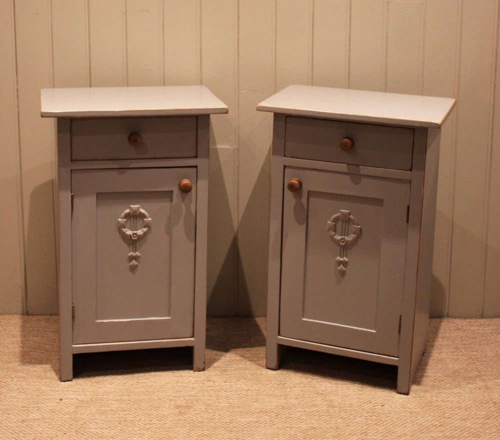 A pair of light grey painted pine bedside cabinets, each featuring a single upper drawer above a cupboard door decorated with a carved wreath motif. View XI