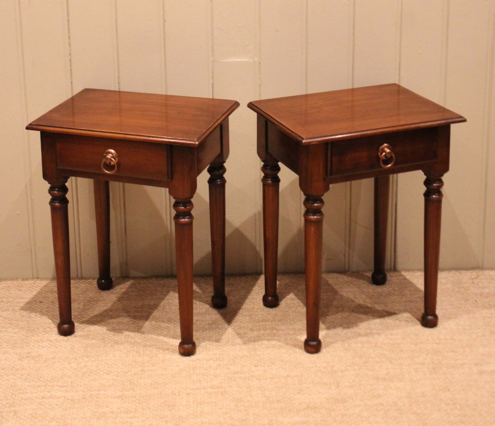 A pair of warm brown French cherry wood bedside tables featuring single drawers with brass ring pulls and slender turned legs. View IV