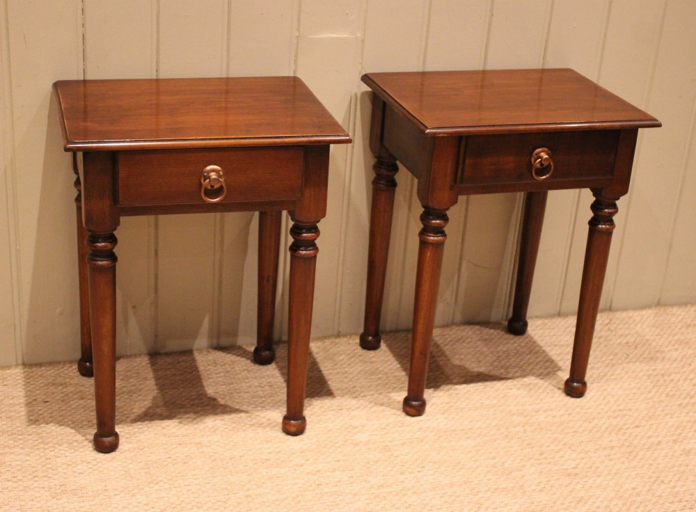 A pair of warm brown French cherry wood bedside tables featuring single drawers with brass ring pulls and slender turned legs. View VI