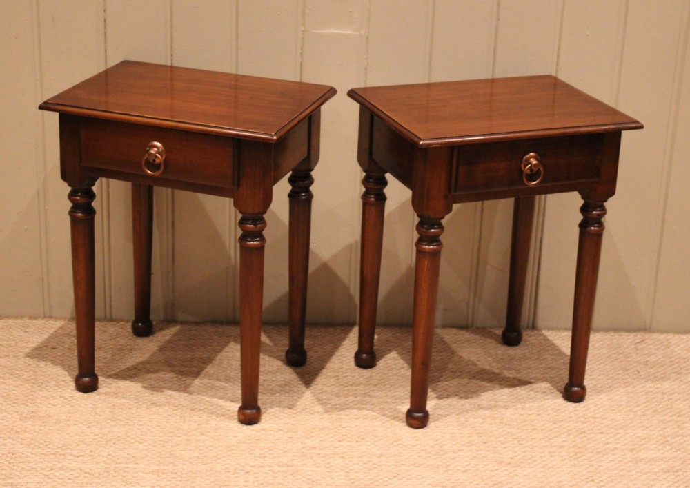 A pair of warm brown French cherry wood bedside tables featuring single drawers with brass ring pulls and slender turned legs. View X