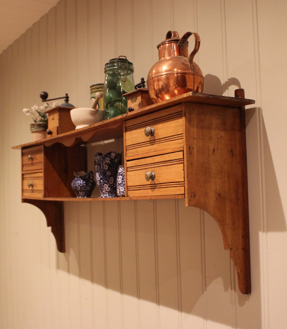 A French poplar wooden wall shelf featuring four side drawers, a central open compartment, and carved lower wall brackets. View V
