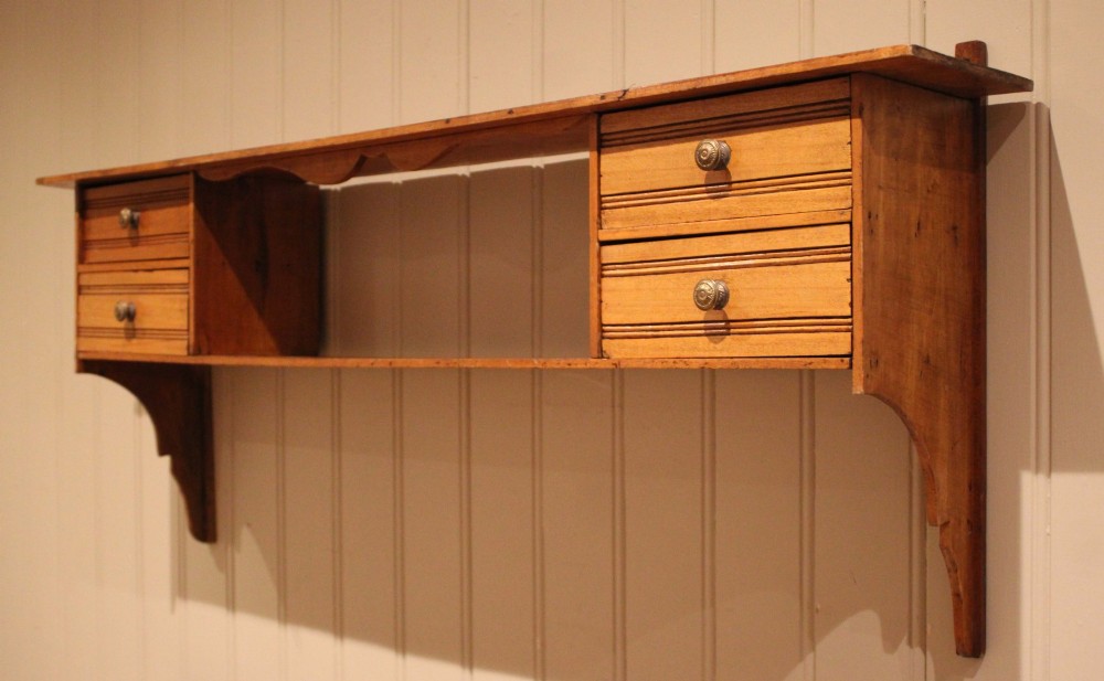 A French poplar wooden wall shelf featuring four side drawers, a central open compartment, and carved lower wall brackets. View VI