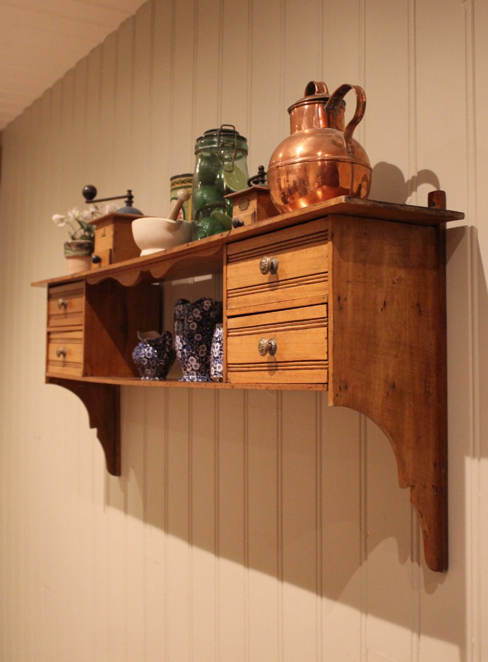 A French poplar wooden wall shelf featuring four side drawers, a central open compartment, and carved lower wall brackets. View VII