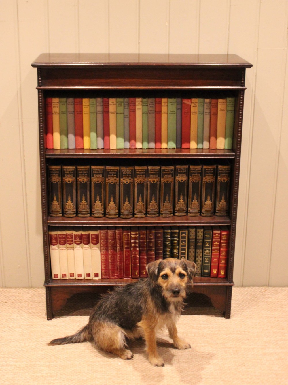 A dark oak open bookcase featuring three adjustable shelves, beaded moulding along the side columns, and a decorative shaped bottom apron with a central circular boss. View V