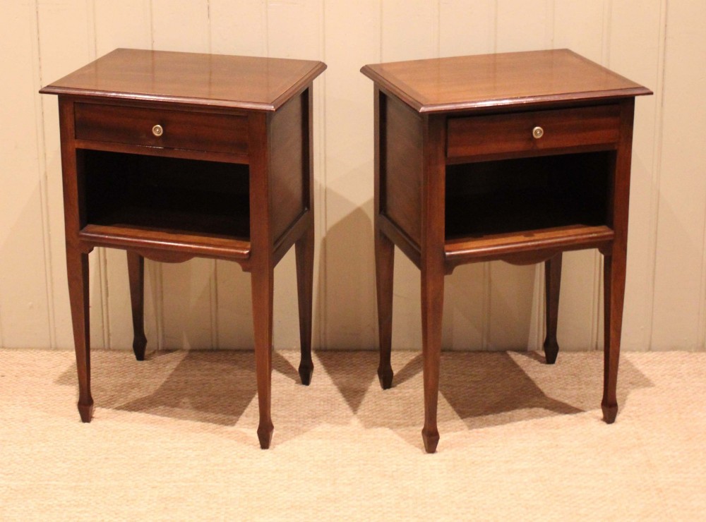 A matching pair of warm brown mahogany bedside tables, each featuring a single top drawer with a central brass knob pull above an open compartment, supported by slender tapered legs. View III