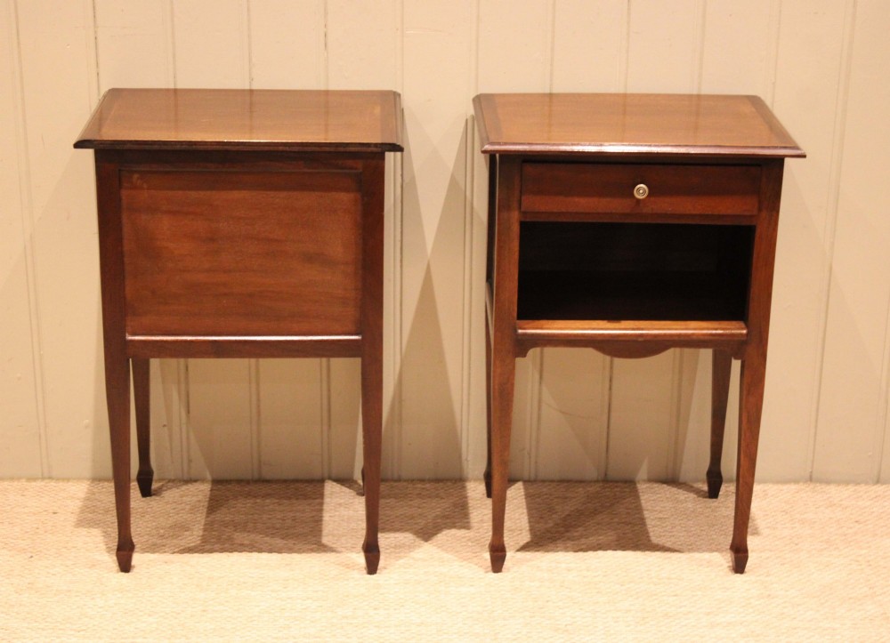 A matching pair of warm brown mahogany bedside tables, each featuring a single top drawer with a central brass knob pull above an open compartment, supported by slender tapered legs. View XI