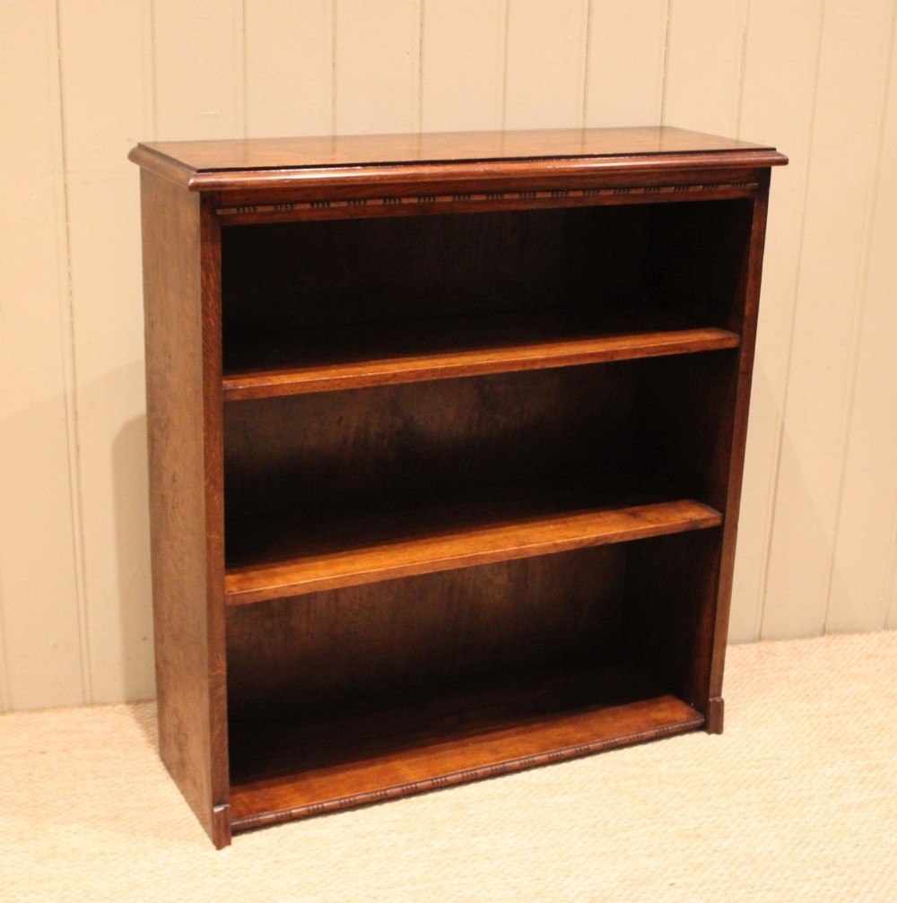 A low open oak bookcase in warm brown featuring three fixed shelves and subtle carved moulding along the top and base edges. View II