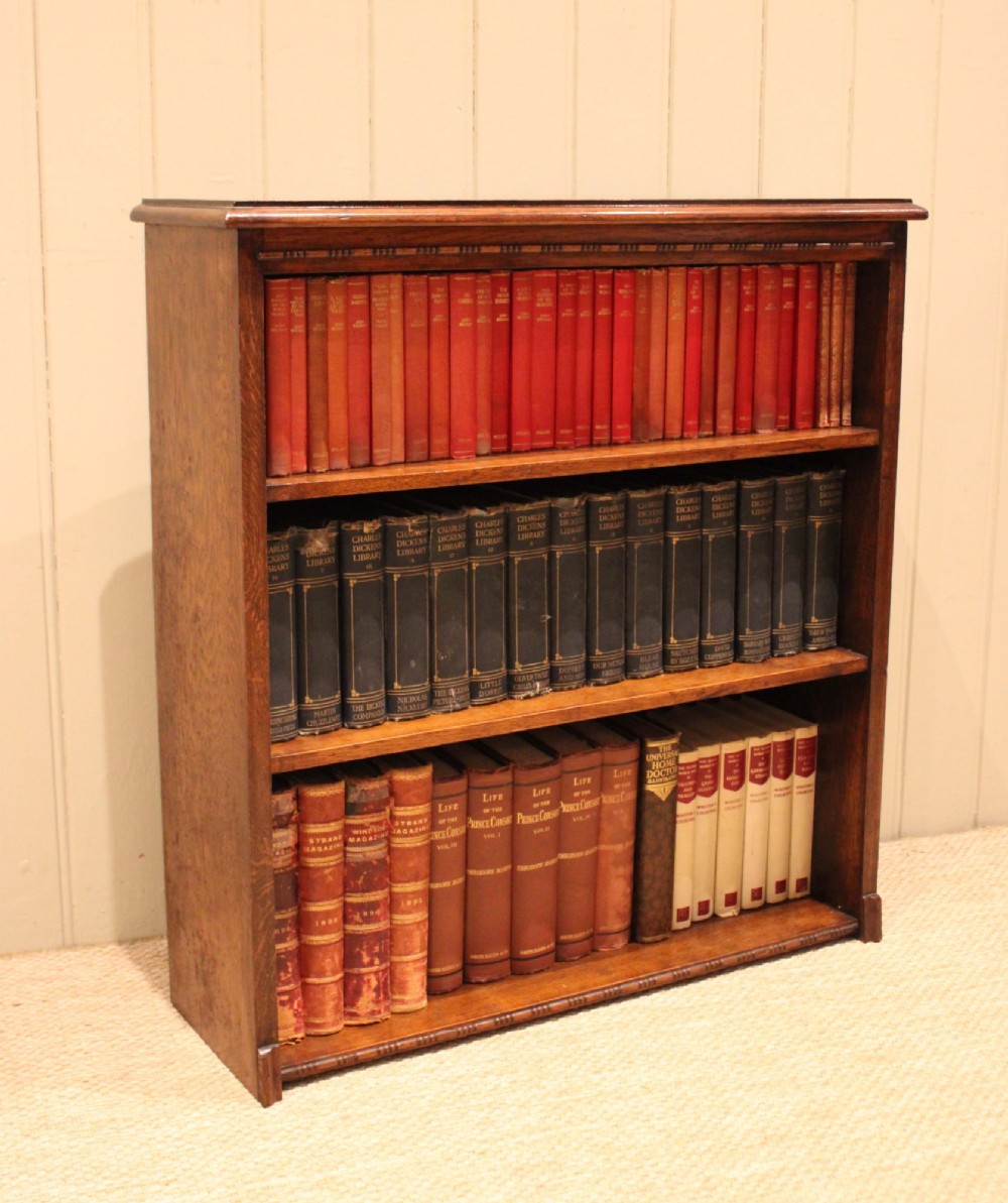 A low open oak bookcase in warm brown featuring three fixed shelves and subtle carved moulding along the top and base edges. View V