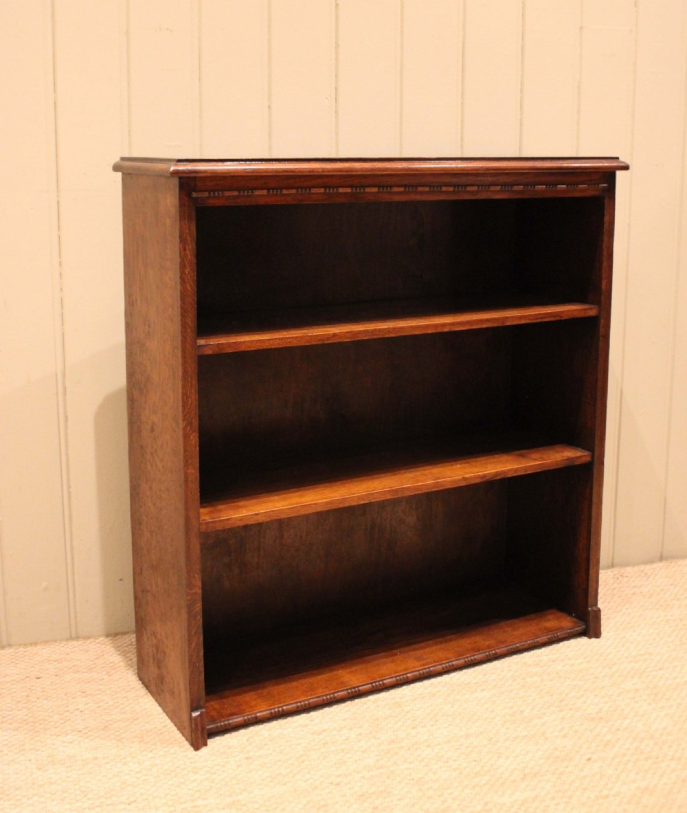 A low open oak bookcase in warm brown featuring three fixed shelves and subtle carved moulding along the top and base edges. View VIII