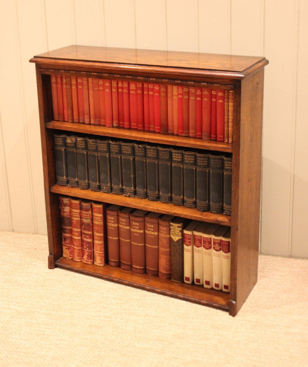 A low open oak bookcase in warm brown featuring three fixed shelves and subtle carved moulding along the top and base edges. View IX