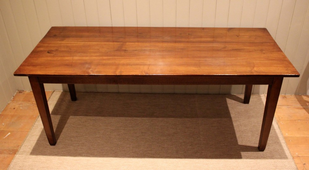 A large rectangular wooden farmhouse table made of chestnut and oak with a polished plank top and simple tapered square legs.