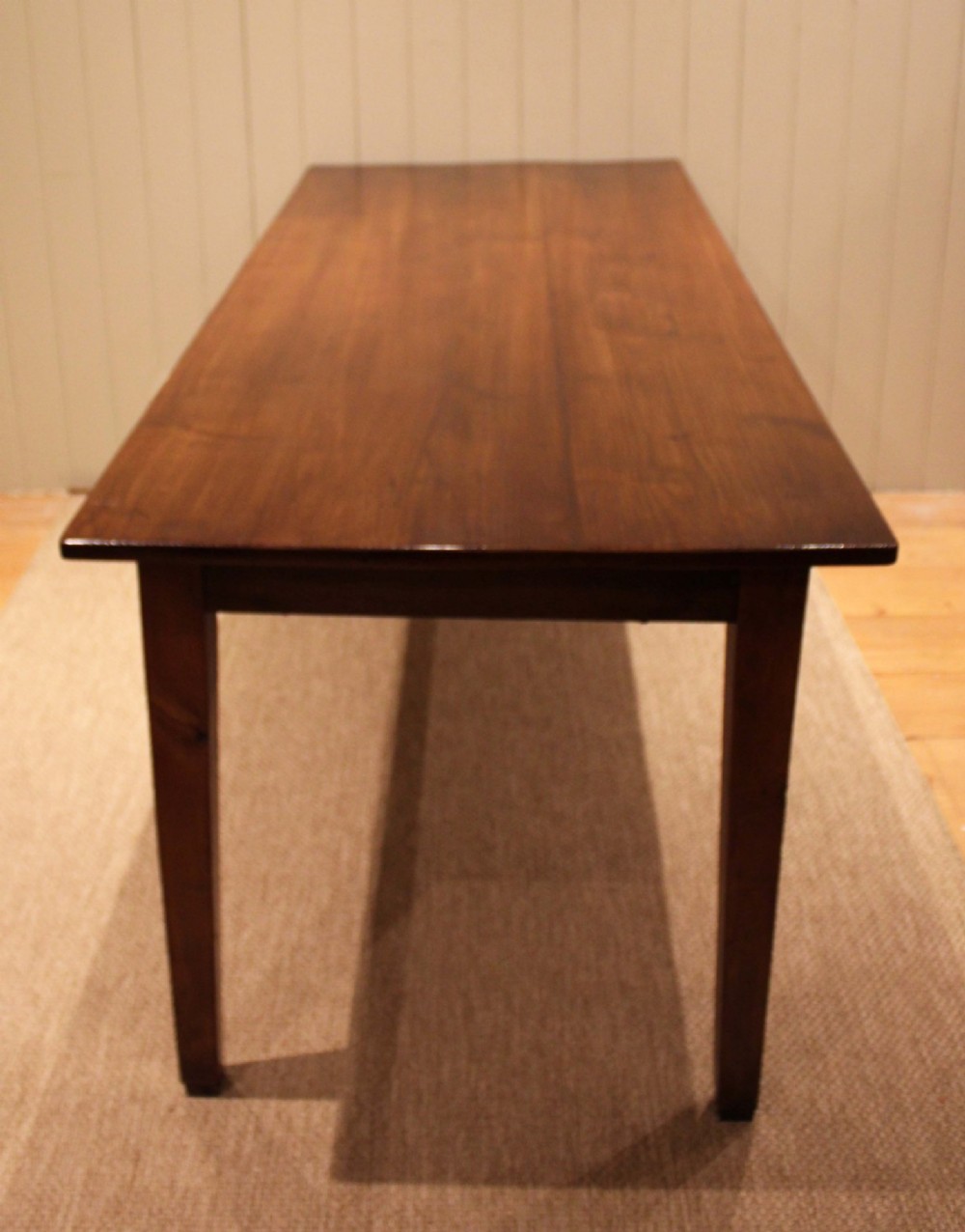 A large rectangular wooden farmhouse table made of chestnut and oak with a polished plank top and simple tapered square legs. View III