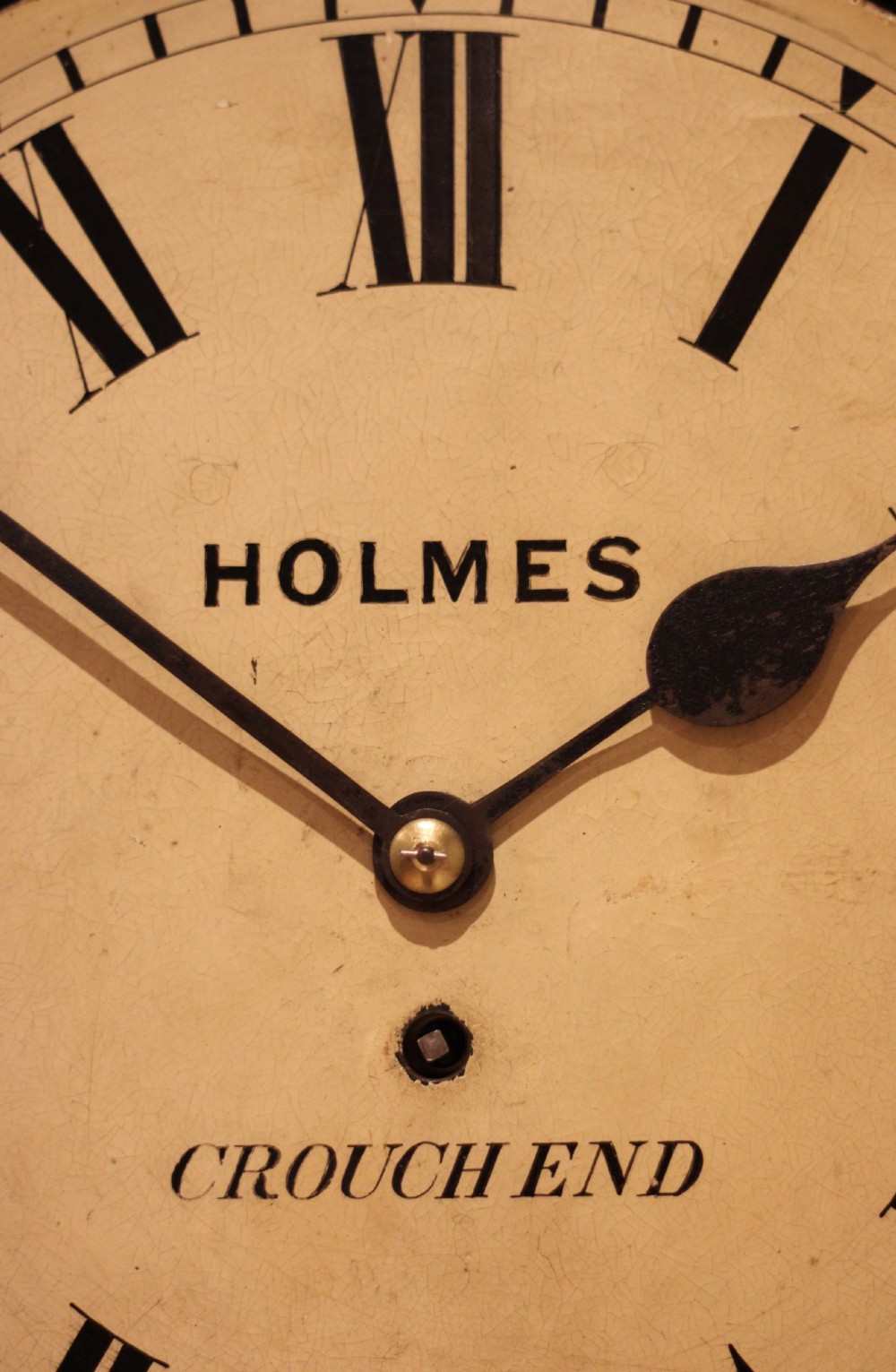 A circular mahogany wall clock featuring a brass bezel surrounding an off-white dial with black Roman numerals. View VI