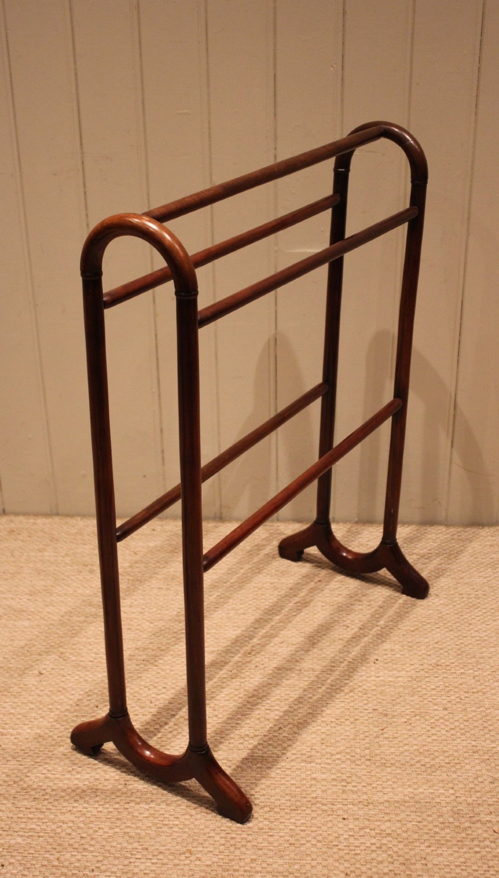 A late 19th-century mahogany freestanding towel rail featuring rounded upright arches, multiple horizontal crossbars, and curved trestle feet.