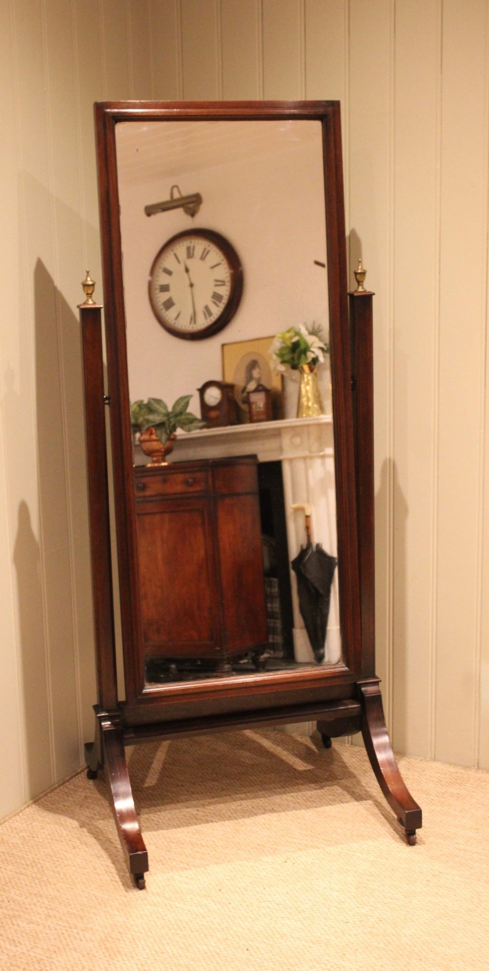 A late nineteenth-century mahogany cheval mirror featuring a rectangular swinging glass frame supported by upright pillars on splayed feet with brass castors. View II