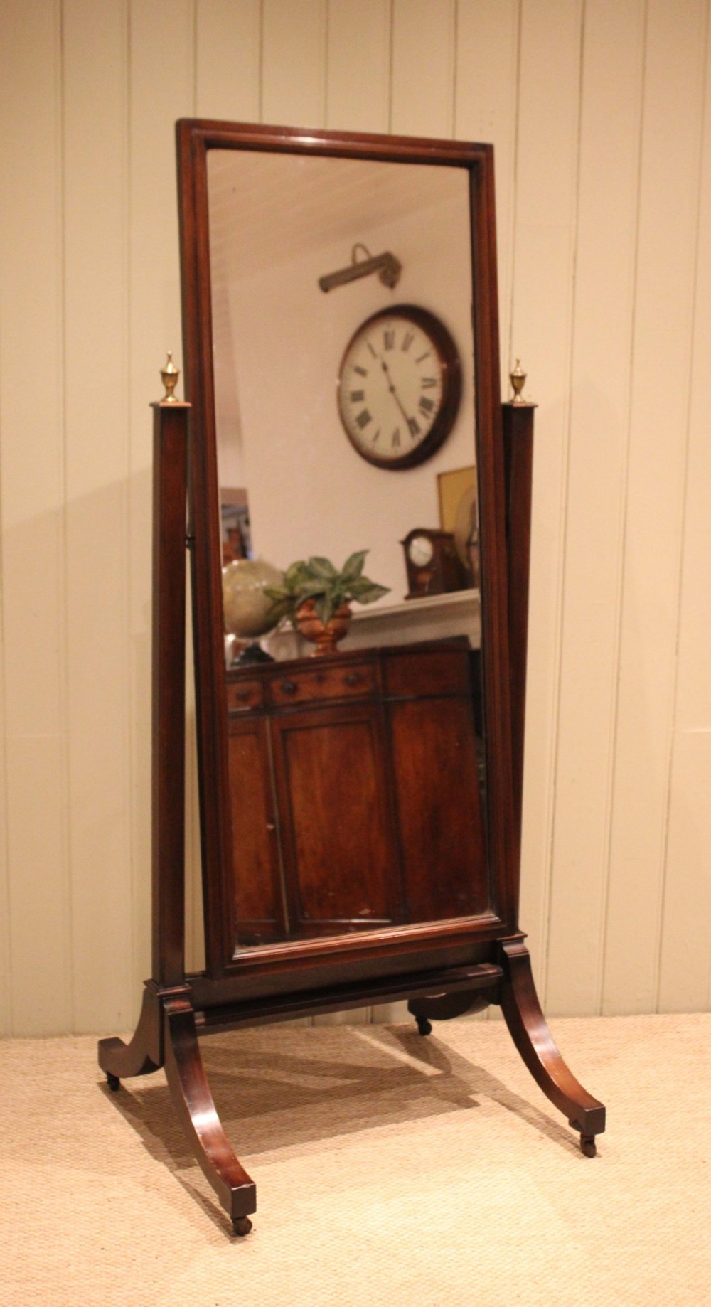 A late nineteenth-century mahogany cheval mirror featuring a rectangular swinging glass frame supported by upright pillars on splayed feet with brass castors. View VI