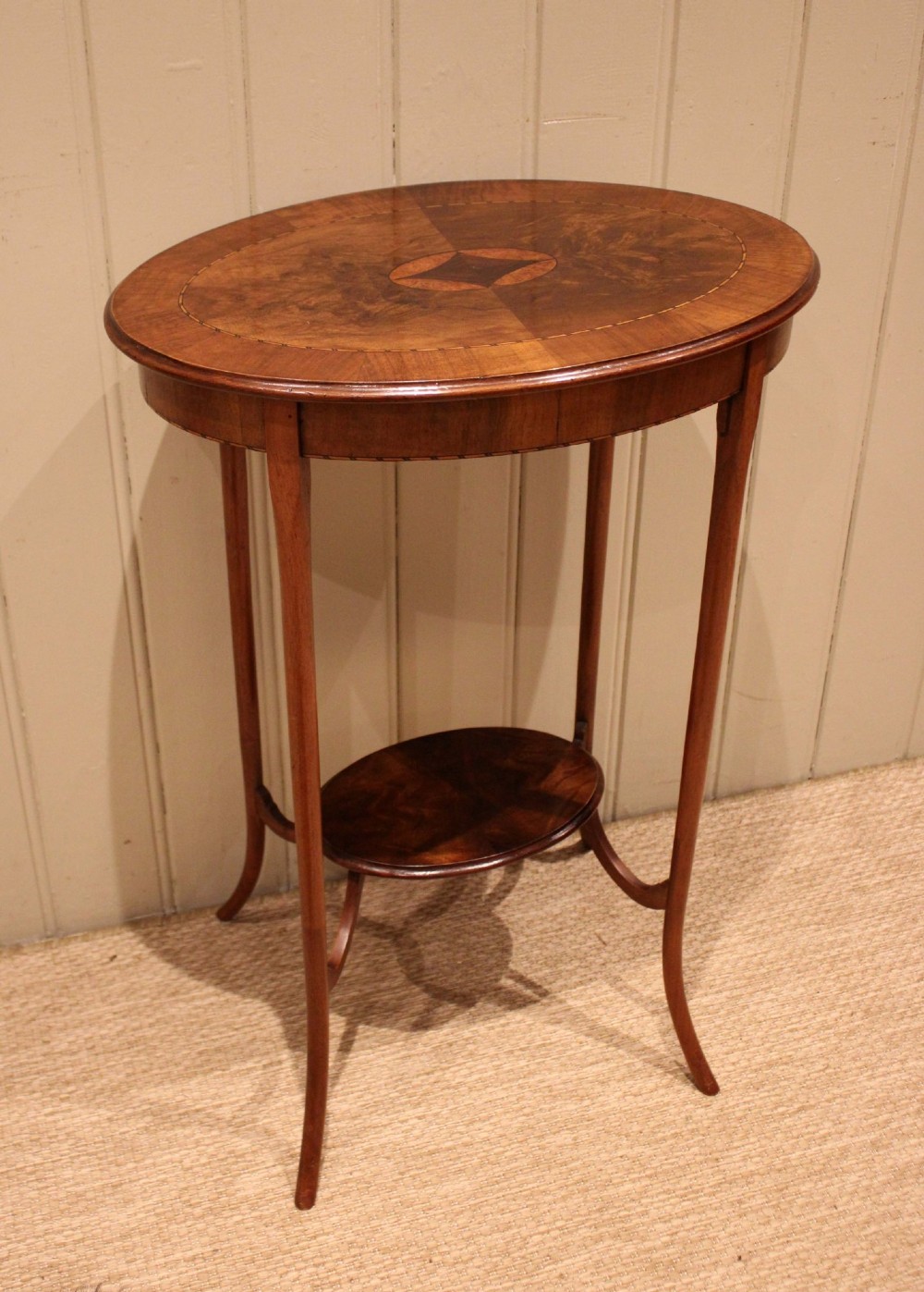 An Edwardian oval mahogany occasional table featuring crossbanded veneer inlay, a central geometric medallion motif, slender swept legs, and a small circular lower shelf. View III
