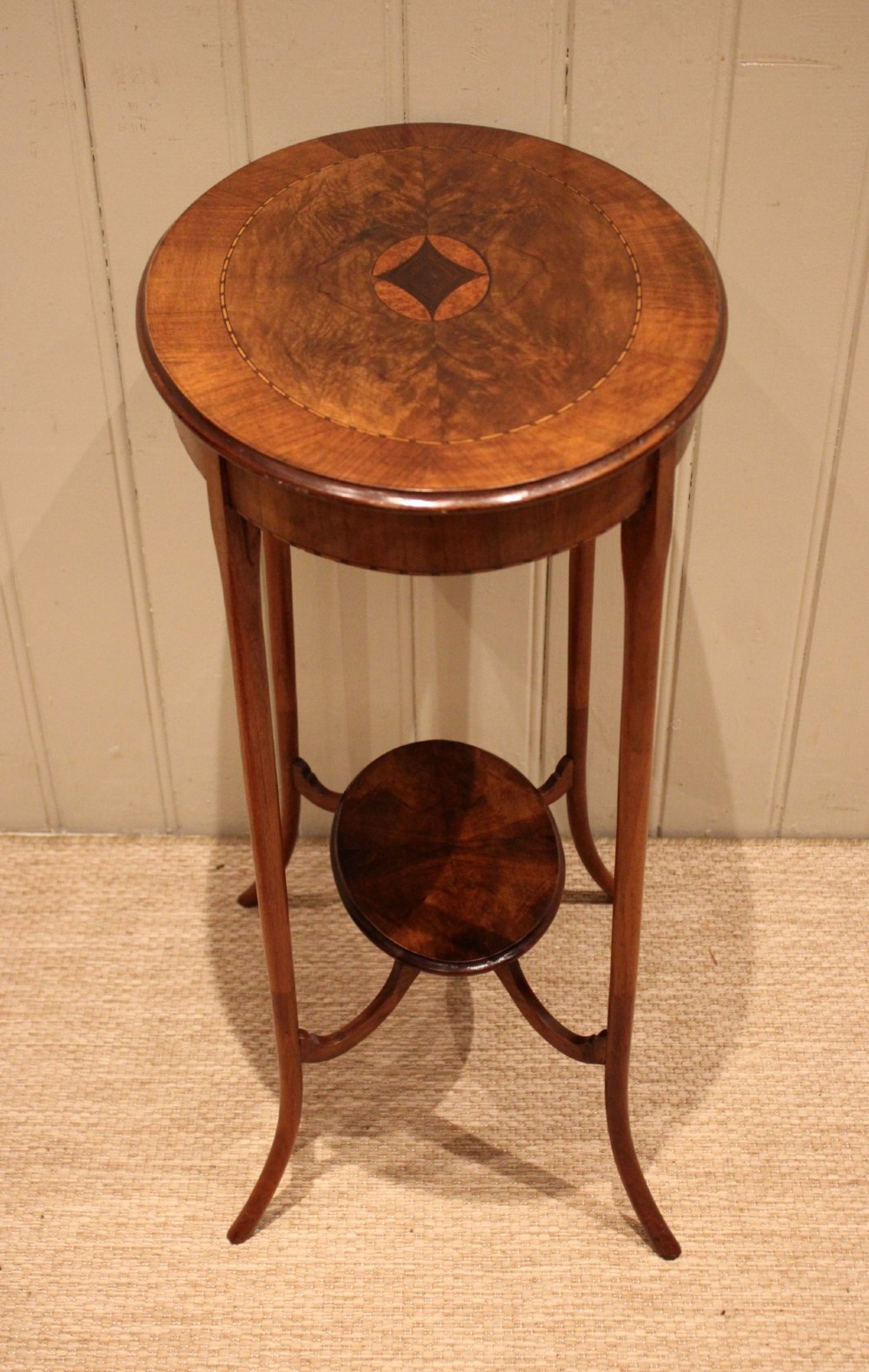 An Edwardian oval mahogany occasional table featuring crossbanded veneer inlay, a central geometric medallion motif, slender swept legs, and a small circular lower shelf. View IX