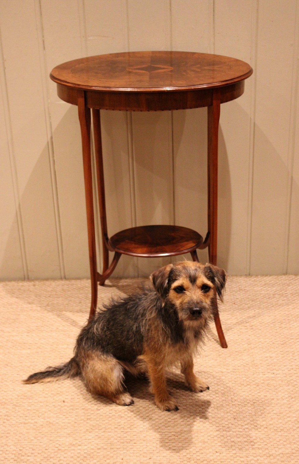 An Edwardian oval mahogany occasional table featuring crossbanded veneer inlay, a central geometric medallion motif, slender swept legs, and a small circular lower shelf. View XII