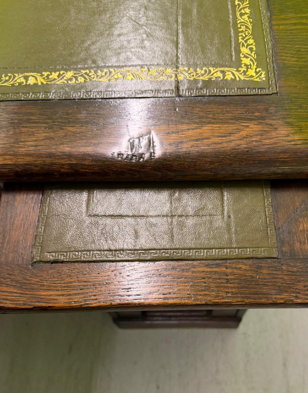 A small solid dark oak clerks desk featuring a leather inset writing surface, a single central drawer, and a four-drawer pedestal on the right. View XII