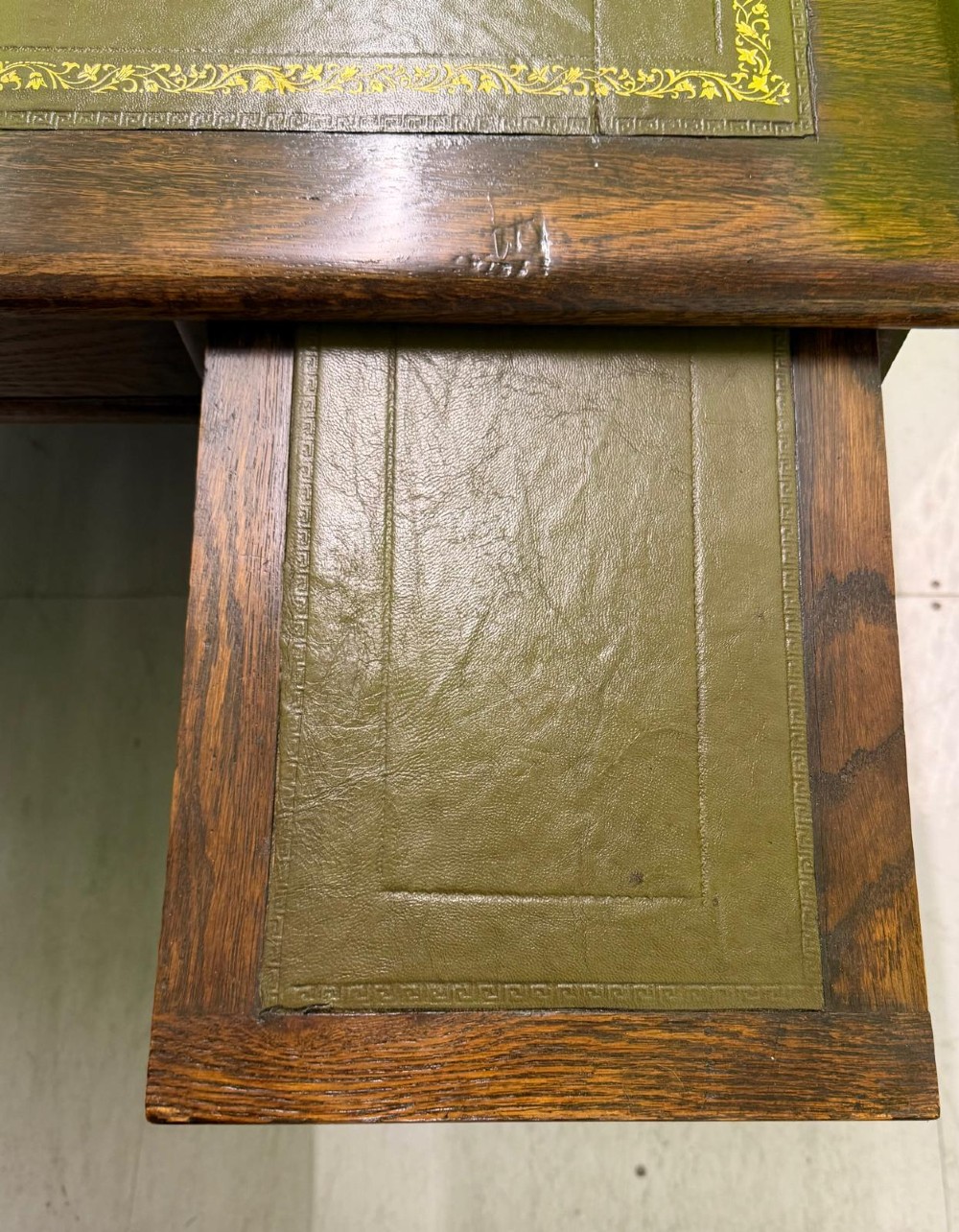 A small solid dark oak clerks desk featuring a leather inset writing surface, a single central drawer, and a four-drawer pedestal on the right. View XIII