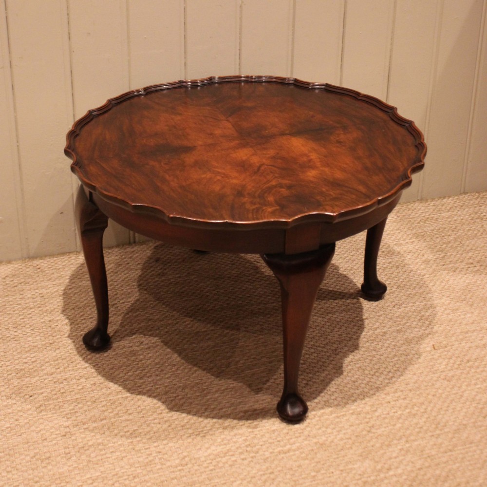 A low circular walnut table featuring a scalloped piecrust edge, quarter-veneered top surface, cabriole legs, and pad feet. View II