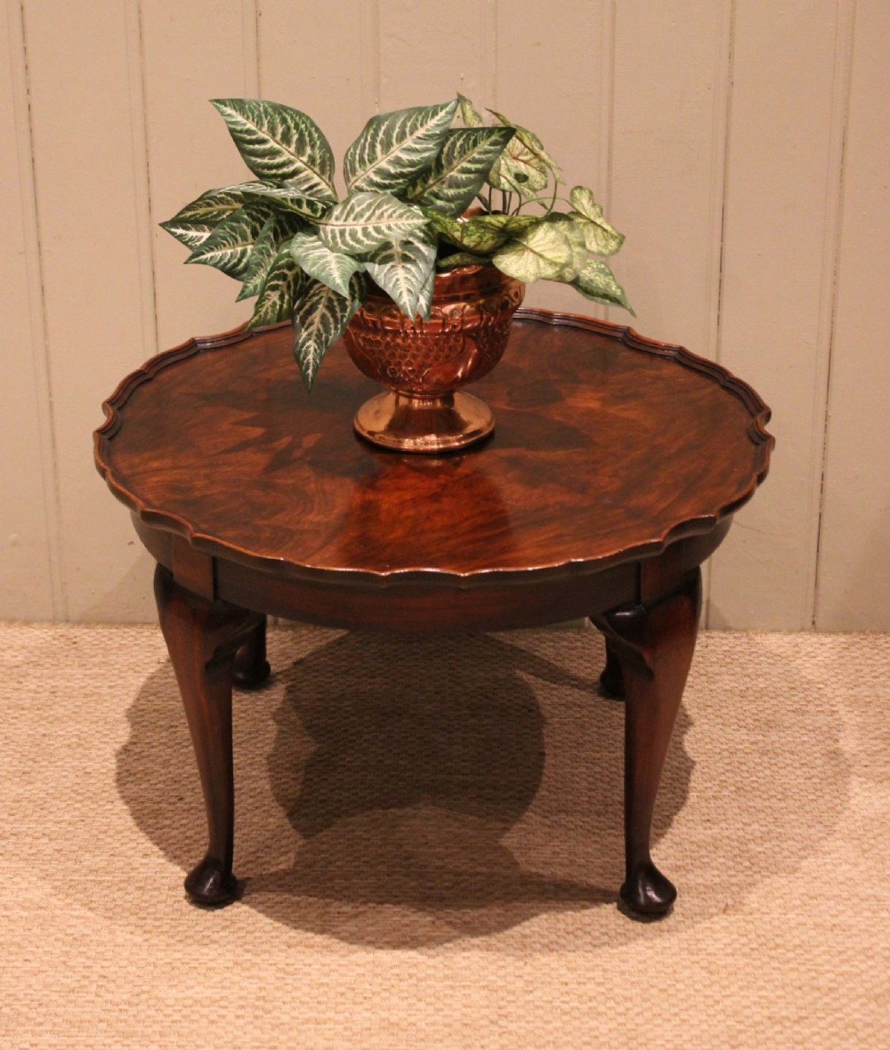 A low circular walnut table featuring a scalloped piecrust edge, quarter-veneered top surface, cabriole legs, and pad feet. View V