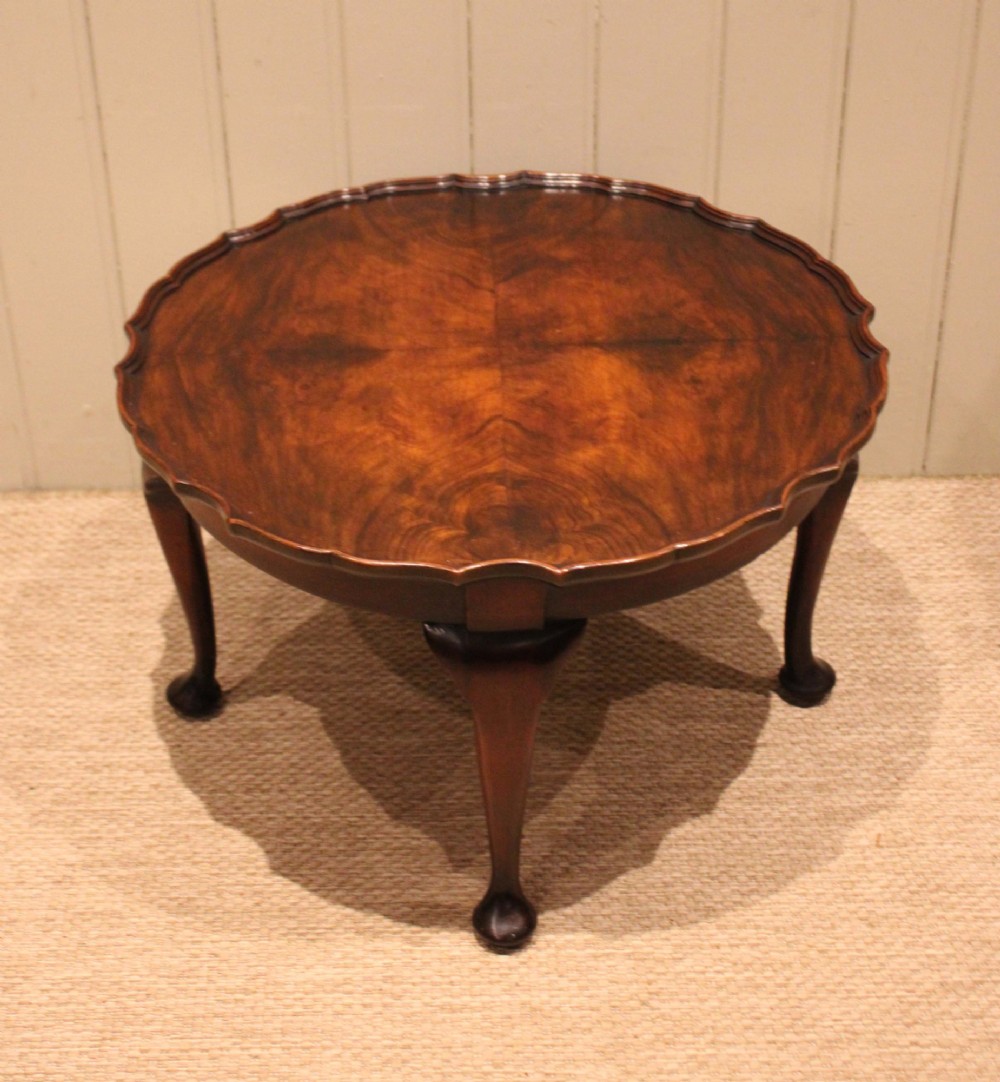 A low circular walnut table featuring a scalloped piecrust edge, quarter-veneered top surface, cabriole legs, and pad feet. View VI