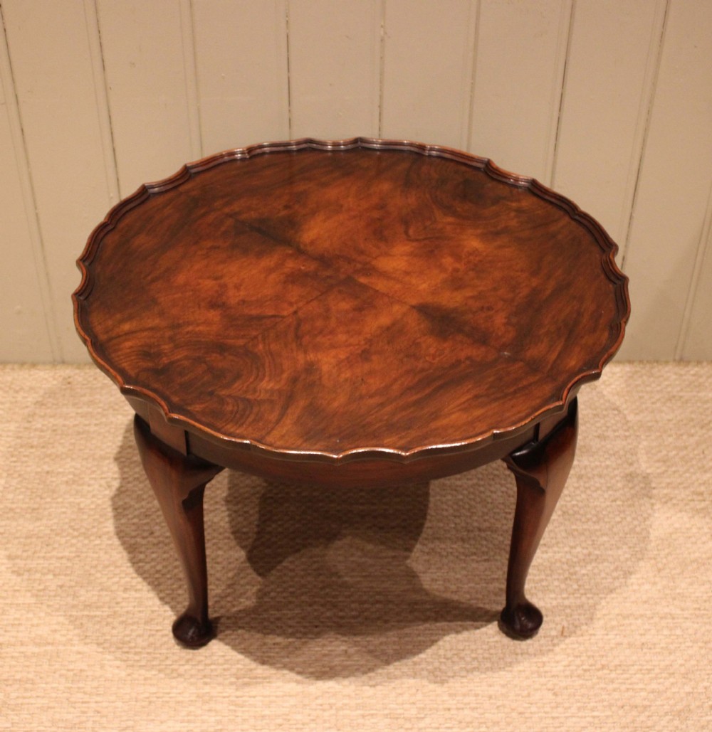 A low circular walnut table featuring a scalloped piecrust edge, quarter-veneered top surface, cabriole legs, and pad feet. View IX