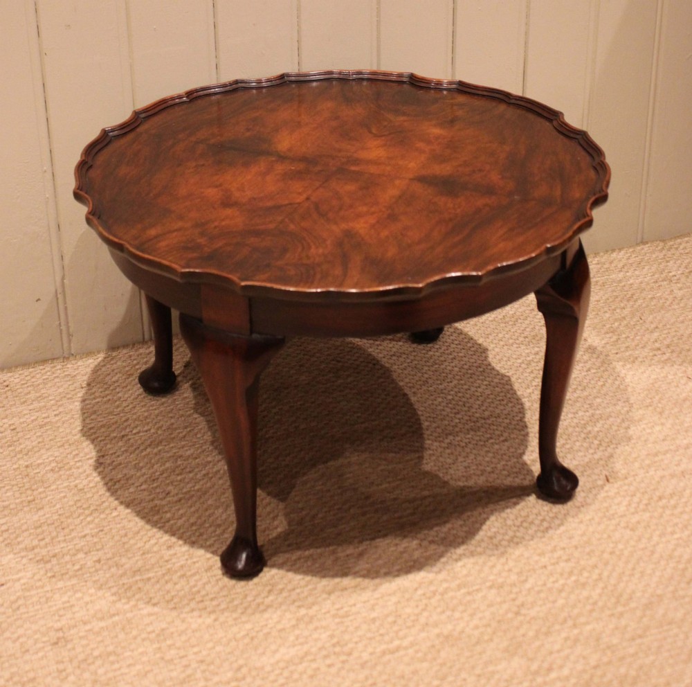 A low circular walnut table featuring a scalloped piecrust edge, quarter-veneered top surface, cabriole legs, and pad feet. View X