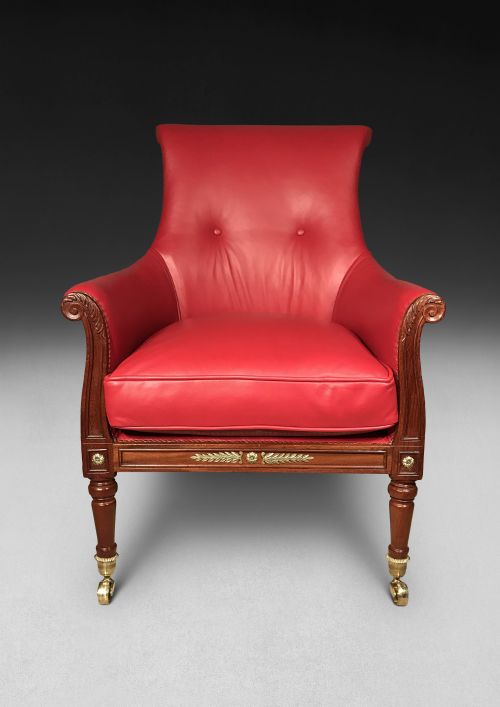 fig 1. A pair of Regency mahogany armchairs upholstered in bright red leather with turned front legs set on brass castors.