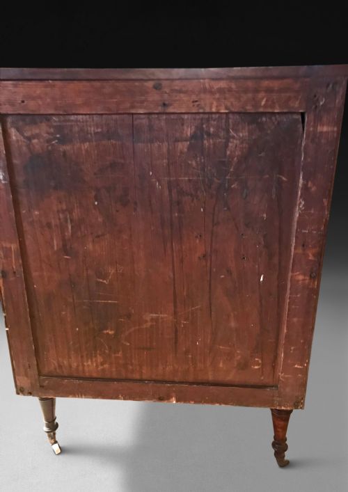 fig 2. A Regency mahogany concave-fronted commode featuring three drawers, ebony line inlay, reeded side columns, turned legs, and brass castors.
