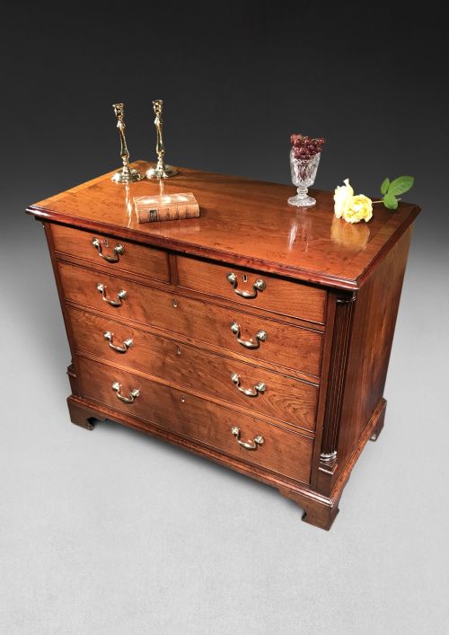 fig 1. A George III mahogany chest of drawers featuring a two-over-three drawer layout, brass swan-neck handles, reeded corner pilasters, and bracket feet.