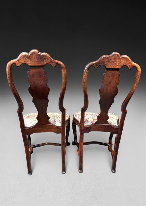 fig 2. A pair of antique George I walnut side chairs featuring carved cresting rails, vase-shaped back splats, floral upholstered drop-in seats, and cabriole front legs.