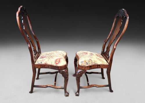 fig 3. A pair of antique George I walnut side chairs featuring carved cresting rails, vase-shaped back splats, floral upholstered drop-in seats, and cabriole front legs.