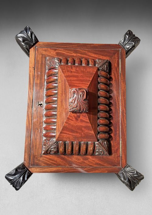 fig 2. A Regency mahogany and ebonised cellarette featuring a sarcophagus-form hinged lid with carved gadrooning, set on heavy scroll corner feet.