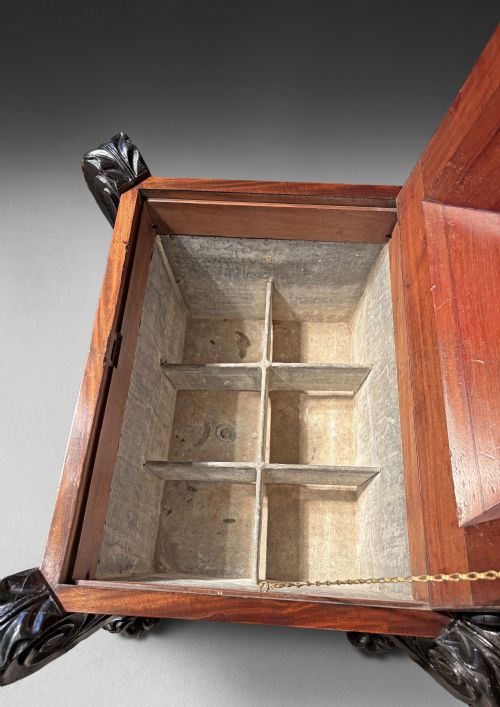 fig 3. A Regency mahogany and ebonised cellarette featuring a sarcophagus-form hinged lid with carved gadrooning, set on heavy scroll corner feet.