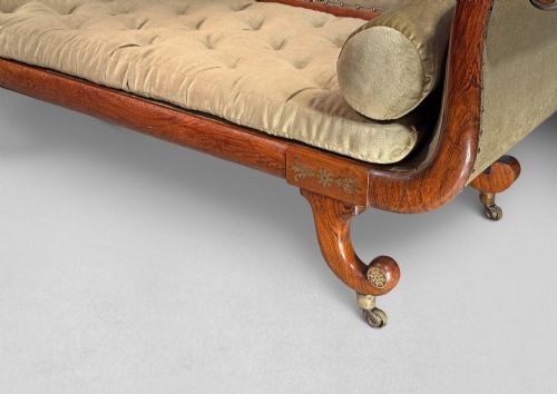 fig 1. Regency simulated rosewood chaise longue with brass inlay, featuring asymmetrical scroll ends, turned brass-castor legs, olive green button-tufted upholstery, and matching bolster cushions.