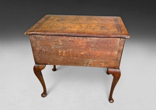 fig 1. A George II period burr walnut lowboy featuring cabriole legs ending in pad feet, multiple drawers with brass drop handles, and a shaped apron.