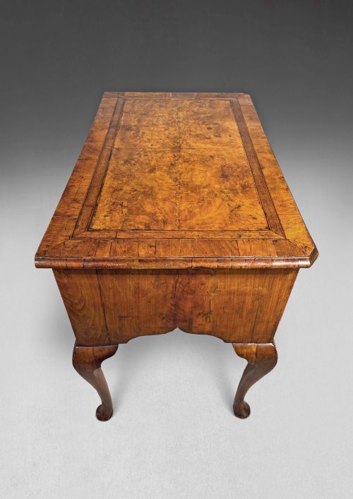 fig 2. A George II period burr walnut lowboy featuring cabriole legs ending in pad feet, multiple drawers with brass drop handles, and a shaped apron.