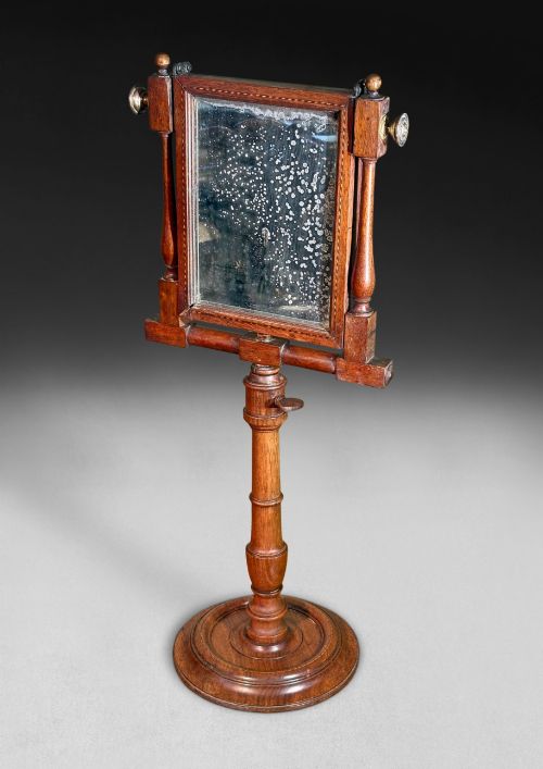 fig 1. A Regency mahogany optical zograscope on a turned pedestal stand featuring an inlaid rectangular frame containing a circular convex magnifying lens above an adjustable mirror.