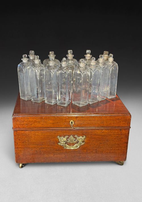 fig 2. An open George III mahogany decanter chest displaying fitted glass decanters, internal compartments, velvet lid lining, and brass hardware.