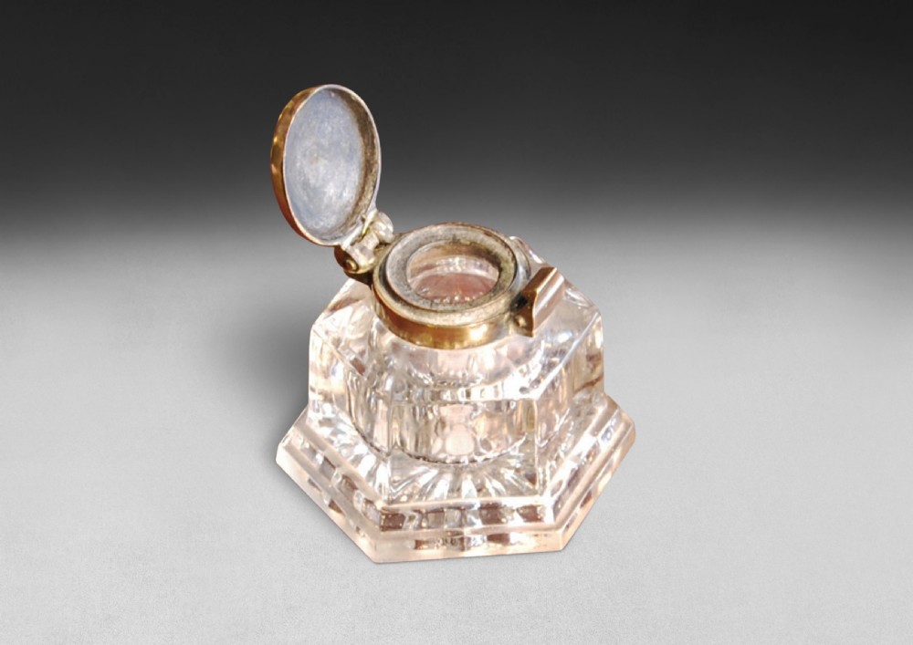 A heavy Victorian cut glass inkwell featuring a hexagonal faceted body and a hinged brass lid. View II