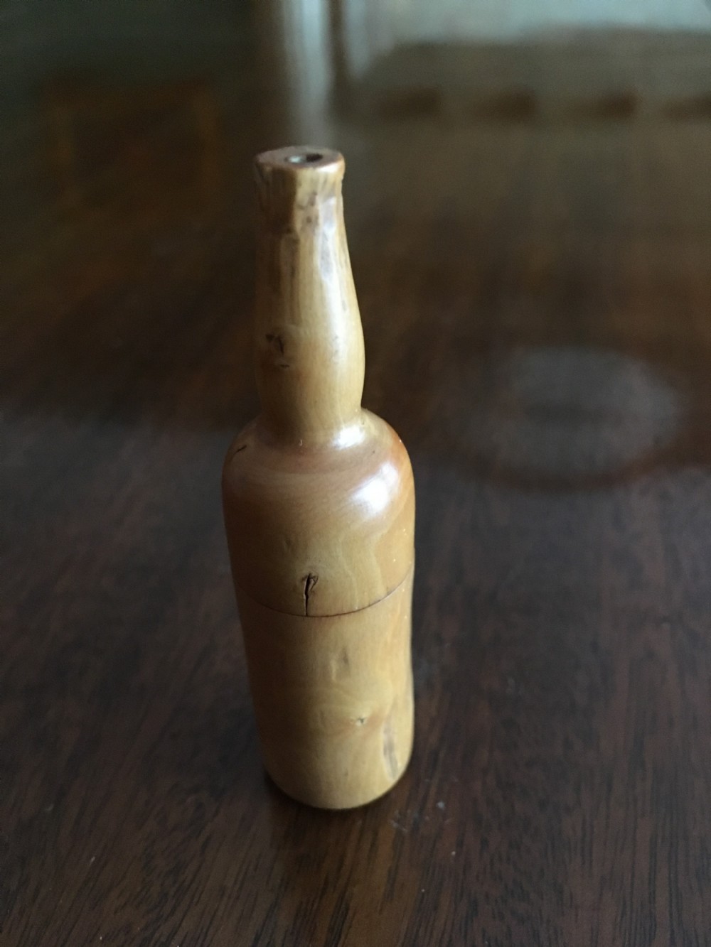 Miniature wooden bottle shaped box containing three small bone dice.