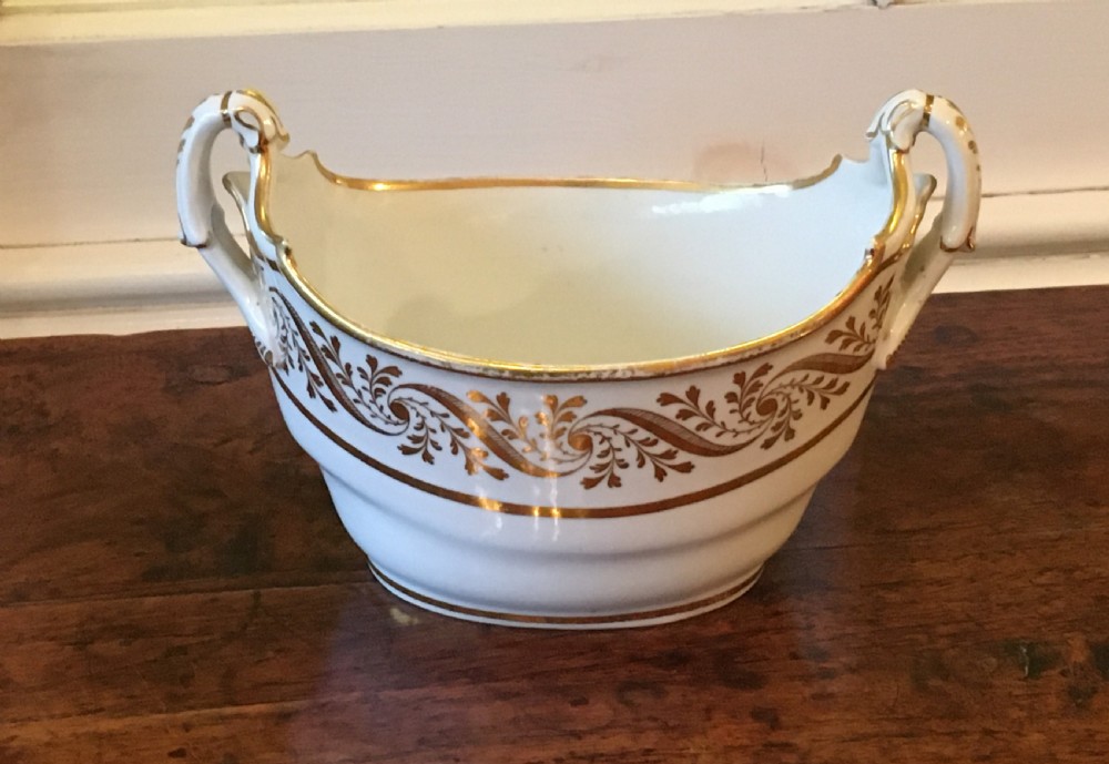 A white boat-shaped antique porcelain sucriere featuring gold leaf foliate scrollwork and twin curved handles.