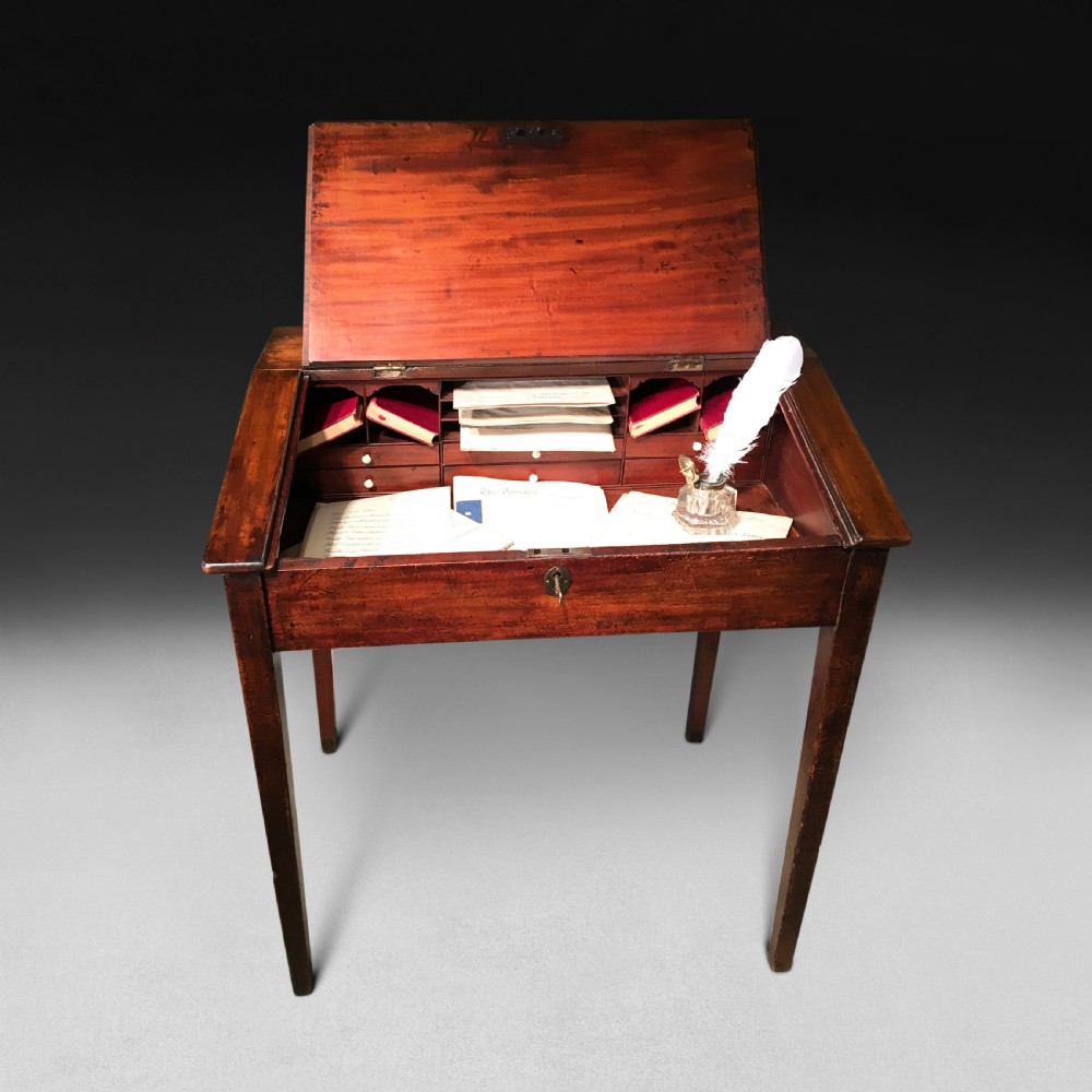 A George III mahogany tally desk featuring a slanted writing surface, a single drawer with a brass keyhole, and four tapered square legs. View II