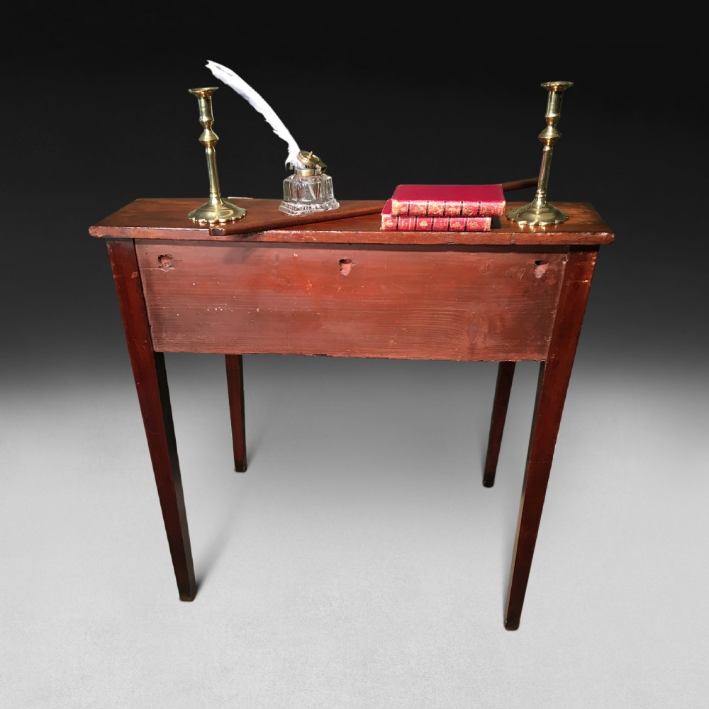 A George III mahogany tally desk featuring a slanted writing surface, a single drawer with a brass keyhole, and four tapered square legs. View IV