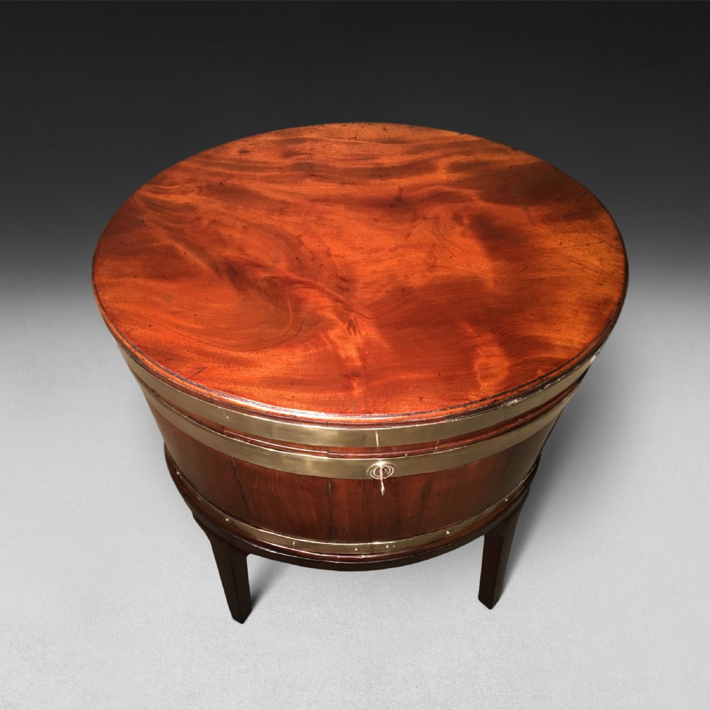A George III period oval mahogany wine cooler on four tapered legs with polished brass structural bands and a fitted hinged lid. View III